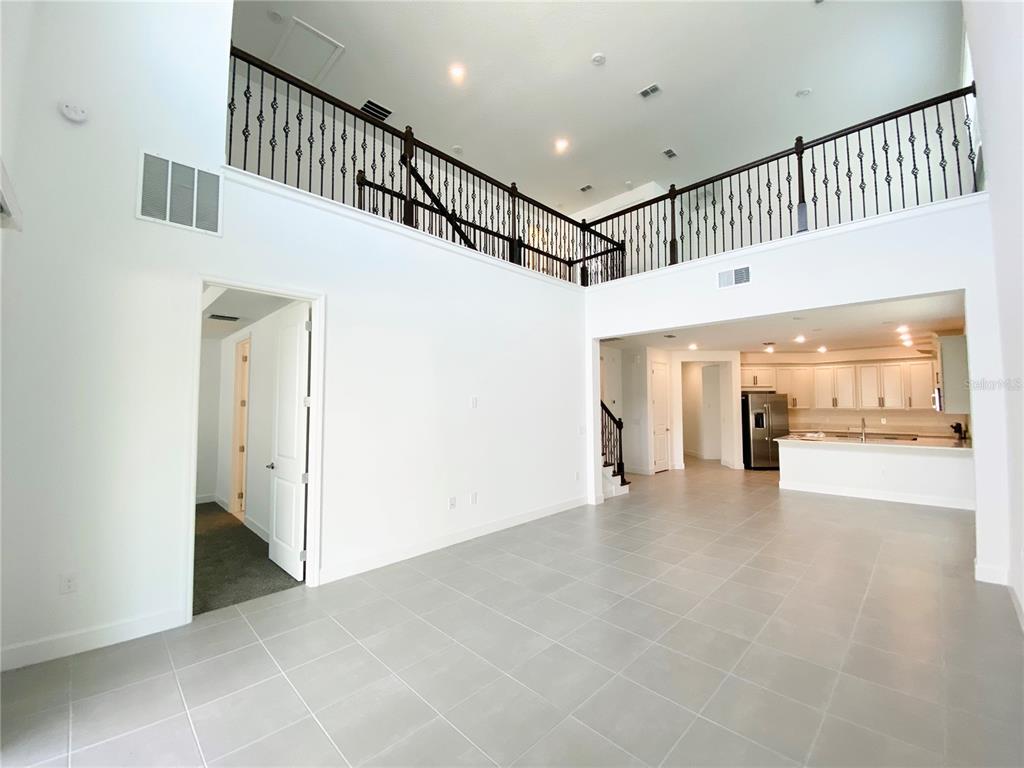 A two-story living area with tile floors, a loft balcony, and an open kitchen — 2348 KESTREL PERCH PLACE, WINTER PARK, FL