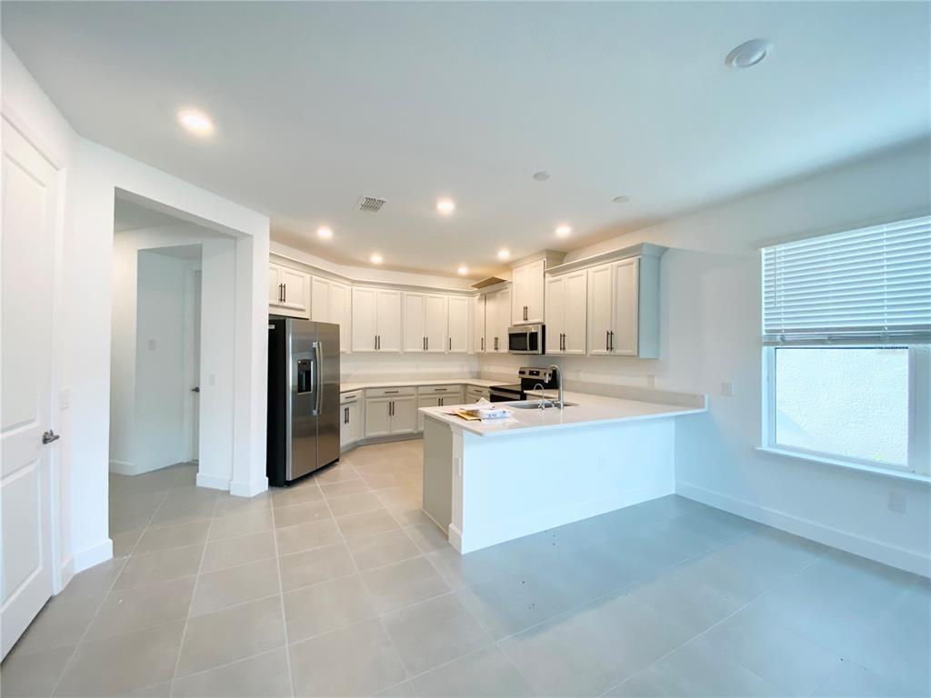 A modern kitchen features white cabinetry, stainless steel appliances, and a peninsula island with countertops — 2348 KESTREL PERCH PLACE, WINTER PARK, FL
