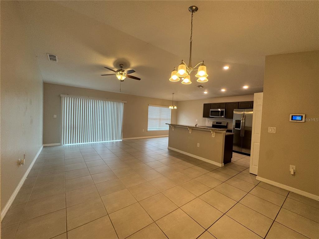 An open-concept living and dining area features tile flooring, a kitchen island, and recessed lighting — 350 W ASTER COURT, POINCIANA, FL