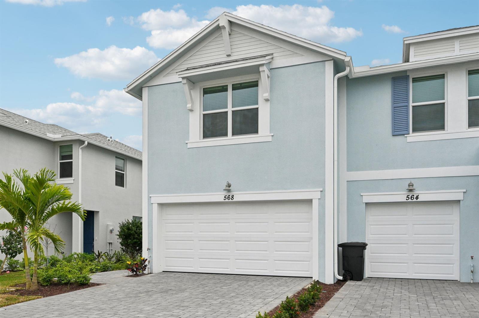 A light blue two-story townhouse exterior features a white garage door and a paved driveway — 568 Salisbury Circle, Fort Pierce FL 34982, FORT PIERCE, FL