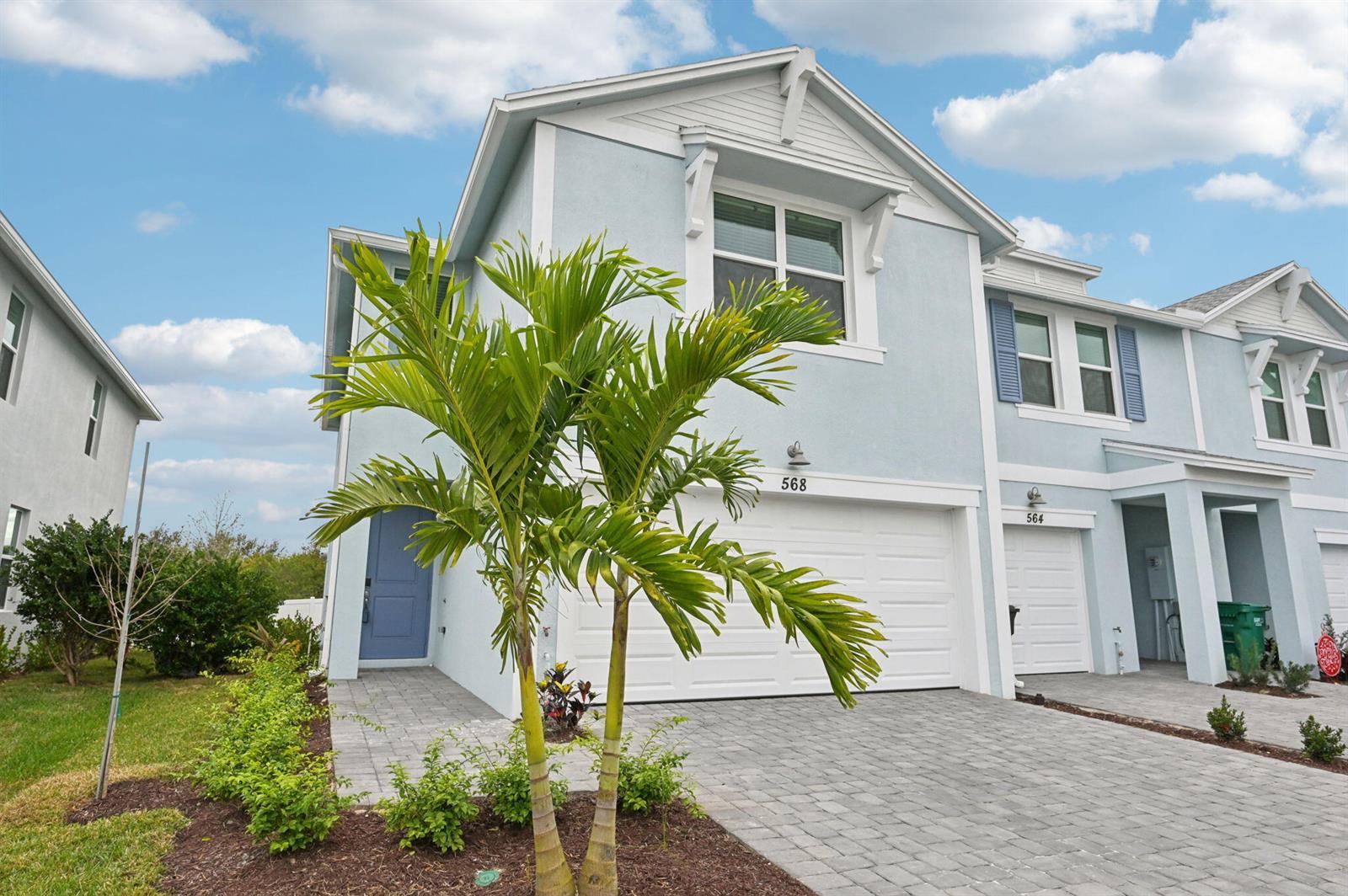 A light blue two-story townhouse with a white garage and a palm tree in front — 568 Salisbury Circle, Fort Pierce FL 34982, FORT PIERCE, FL