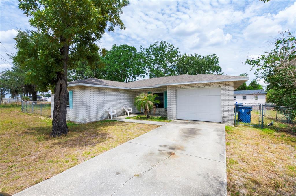 A single-story brick house with a concrete driveway, a one-car garage, and a front lawn — 1915 N 18TH STREET, HAINES CITY, FL
