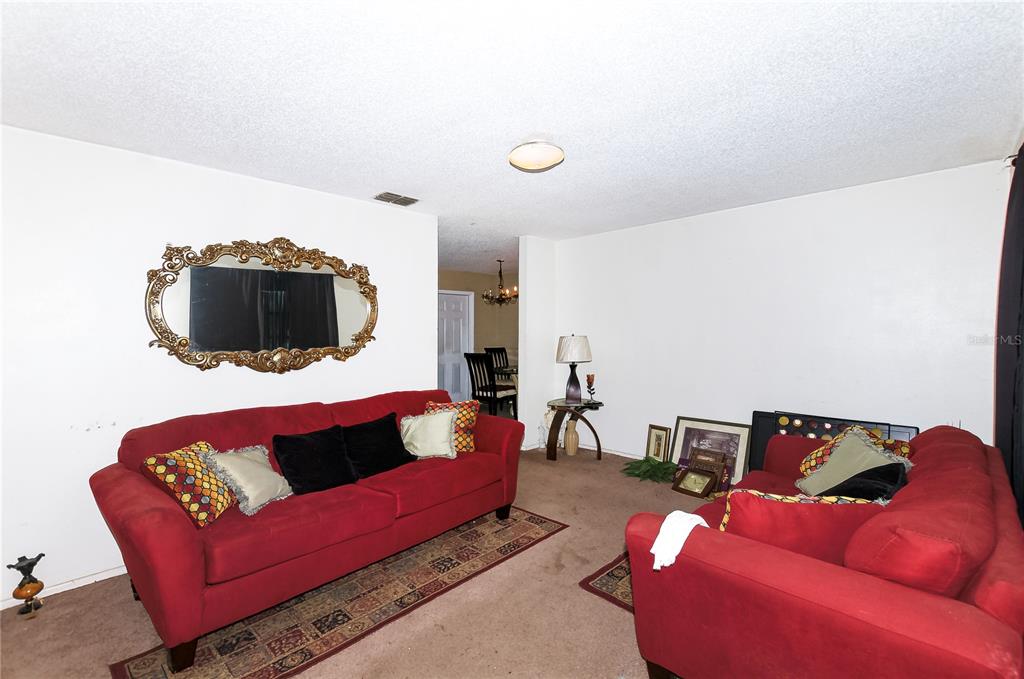 A living room features two red sofas, a large ornate mirror, and brown carpeting — 1915 N 18TH STREET, HAINES CITY, FL