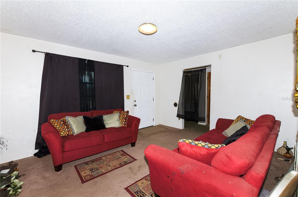 A living room features two red sofas, brown carpeting, and a white front door — 1915 N 18TH STREET, HAINES CITY, FL