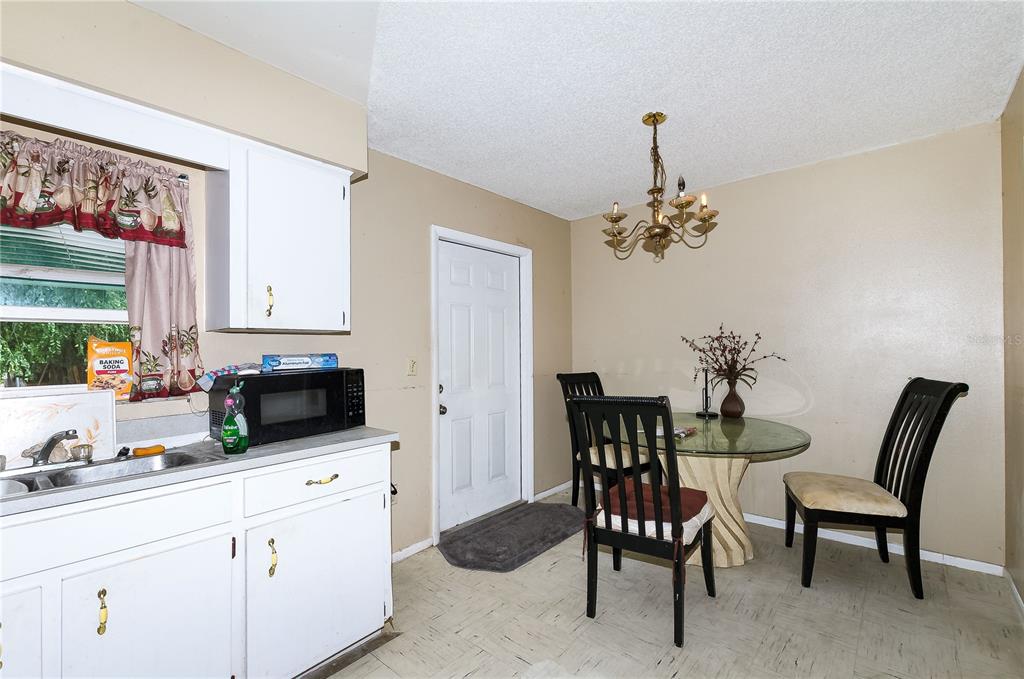 A kitchen with white cabinets, a dining table with three chairs, and a chandelier — 1915 N 18TH STREET, HAINES CITY, FL