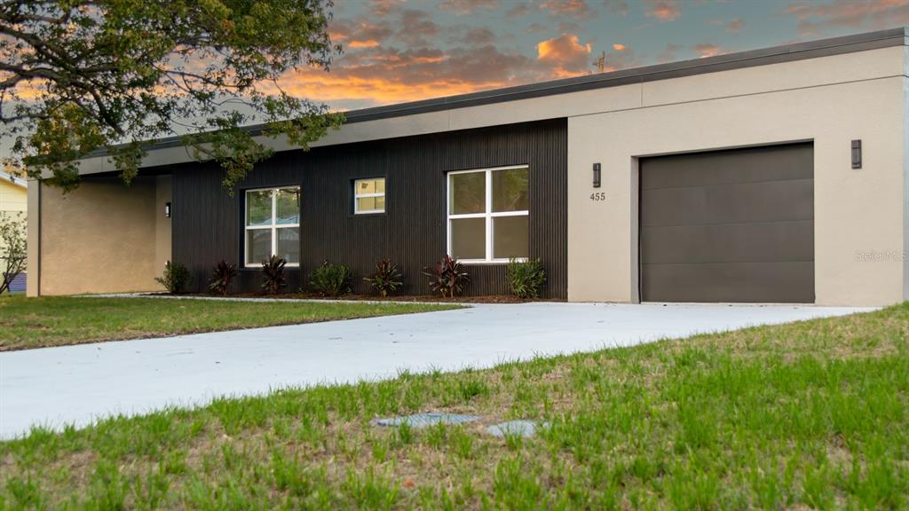 A modern, single-story house features a dark vertical-siding facade, a garage, and a concrete driveway — 455 RIVERVIEW AVENUE, SANFORD, FL
