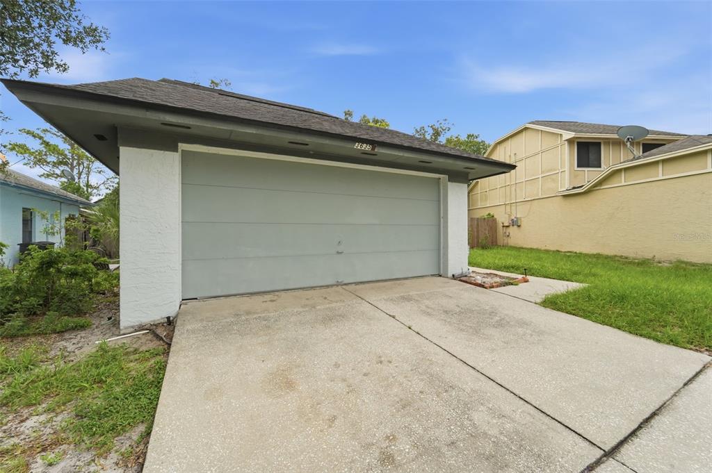 A detached garage with a light gray door and white stucco walls under a roof — 3635 S SAINT LUCIE DRIVE, CASSELBERRY, FL