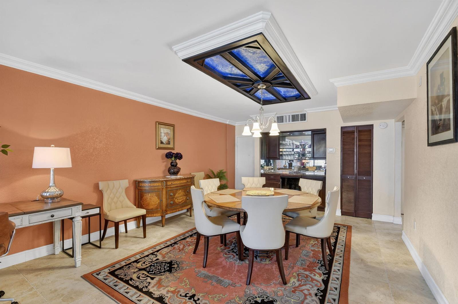 A dining room features a round table, a decorative ceiling light fixture, and orange walls — 3450 S Ocean Boulevard # 520, Palm Beach FL 33480, PALM BEACH, FL
