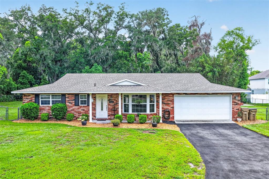 A single-story brick house with a shingled roof, a two-car garage, and a front lawn — 31151 DEAL DRIVE, MOUNT PLYMOUTH, FL
