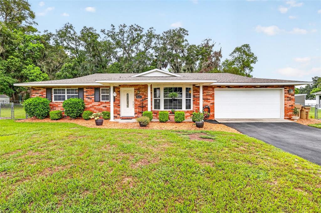 A single-story brick house with a white front door and an attached two-car garage — 31151 DEAL DRIVE, MOUNT PLYMOUTH, FL