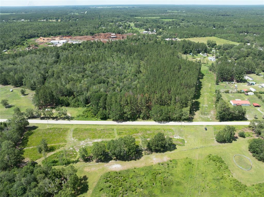 An aerial view shows a large wooded lot bordered by a road and open fields — NW 185TH STREET, STARKE, FL