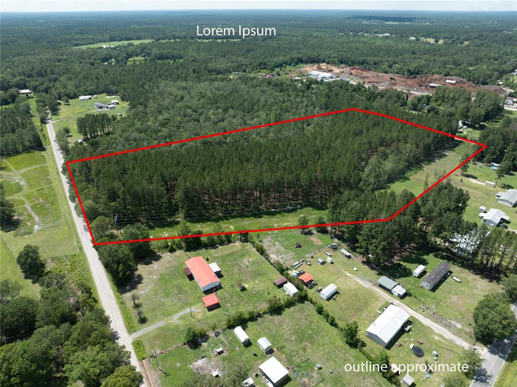 An aerial view shows a wooded plot of land outlined in red near rural houses — NW 185TH STREET, STARKE, FL