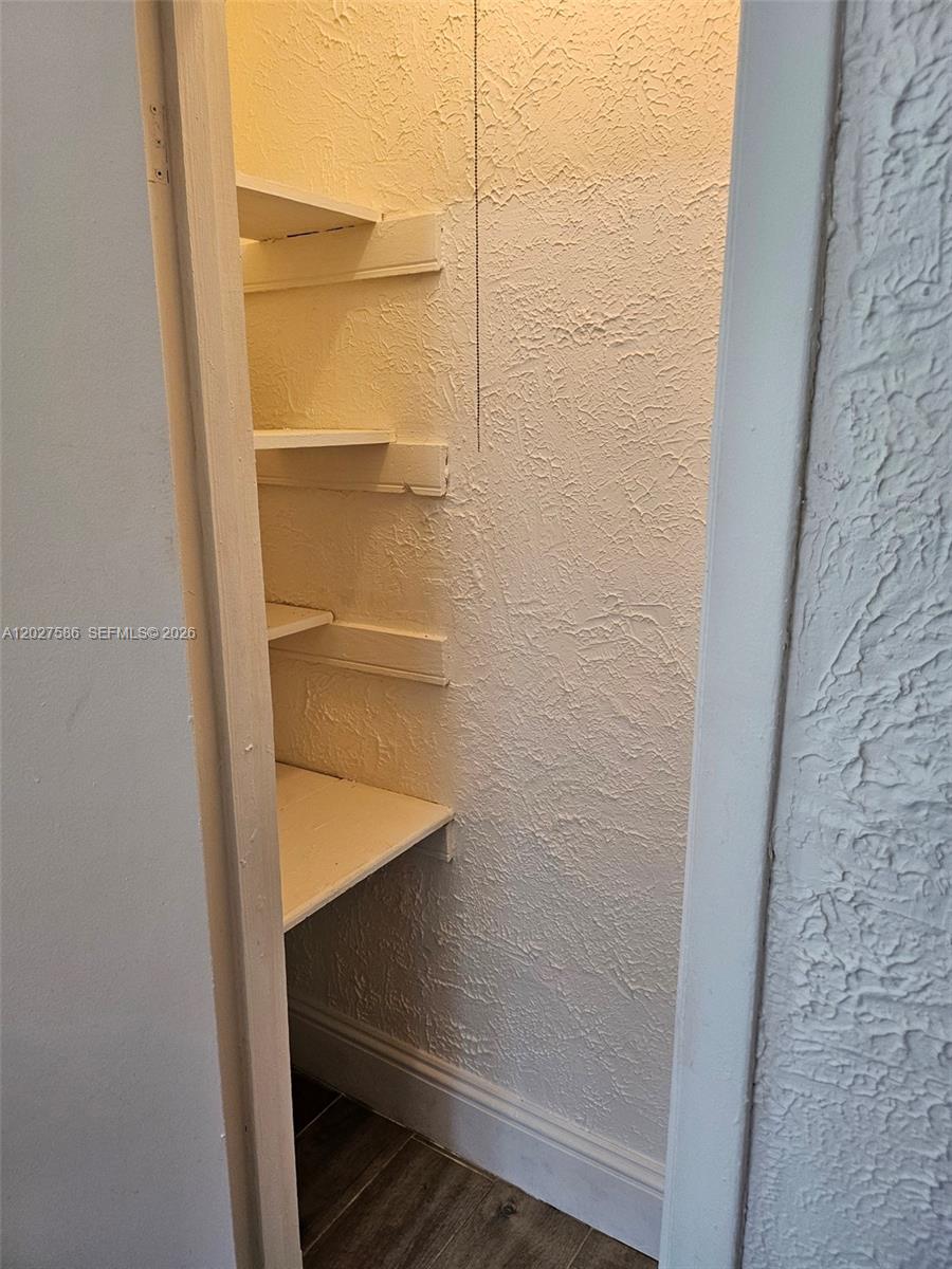 A small closet features white textured walls and several open wooden shelves — 709 NE 4th Ct # 2, Hallandale Beach FL 33009, HALLANDALE BEACH, FL