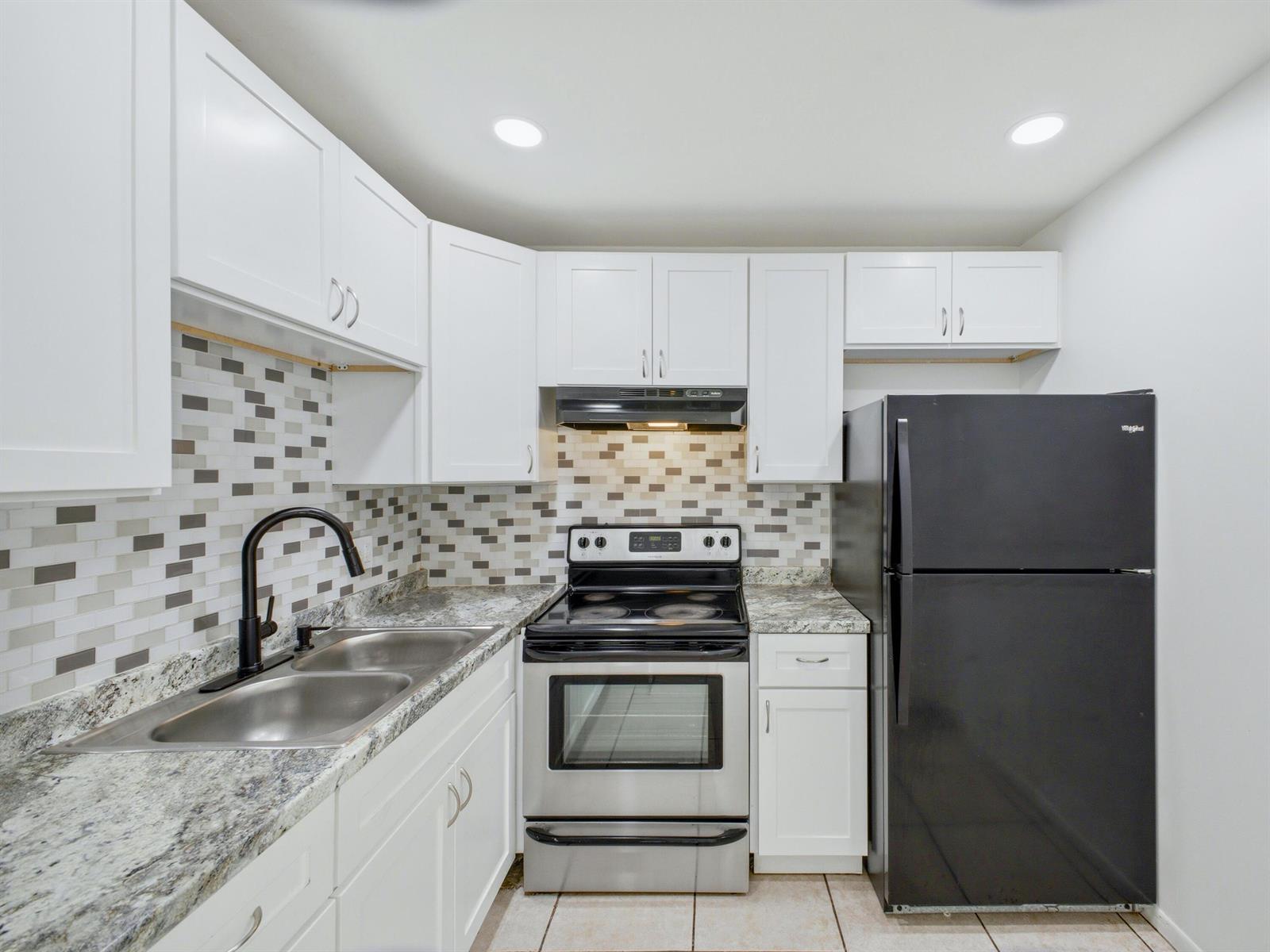 A kitchen features white cabinets, granite countertops, a stainless steel stove, and a black refrigerator — 6289 Lear Drive # 206, Lake Worth FL 33462, LAKE WORTH, FL