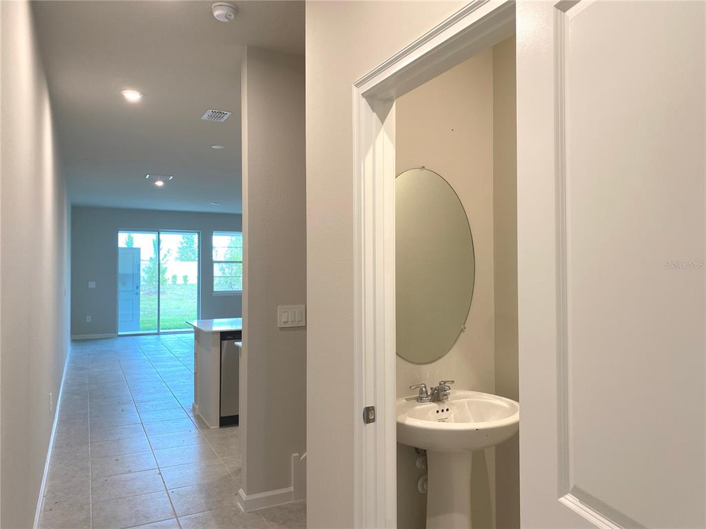 A hallway leads to a kitchen and sliding glass doors, with a powder room nearby — 8850 GINKO RUN, PARRISH, FL