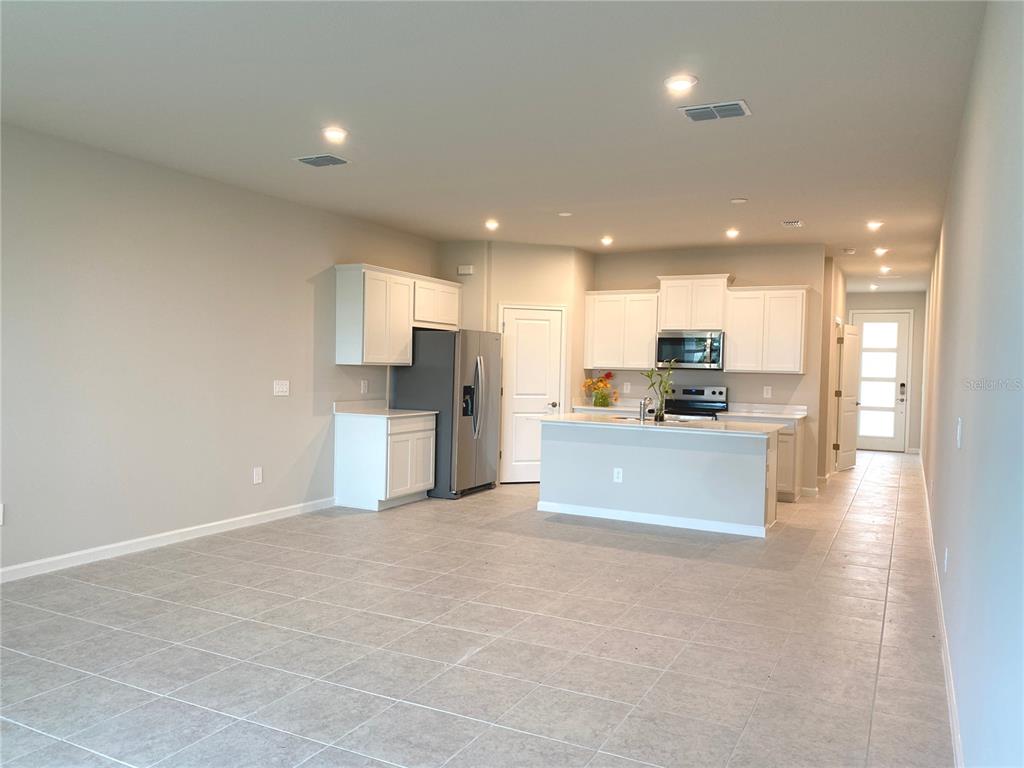 A kitchen with white cabinets, stainless steel appliances, and an island on a tiled floor — 8850 GINKO RUN, PARRISH, FL