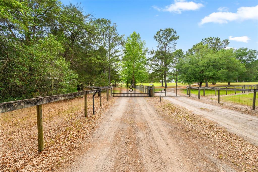 A covered porch features a concrete floor, white columns, and a view of landscaping — 8822 NW 170TH STREET, ALACHUA, FL