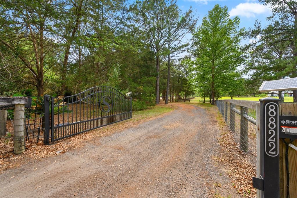 A white single-story house with a metal roof sits behind a stone retaining wall — 8822 NW 170TH STREET, ALACHUA, FL