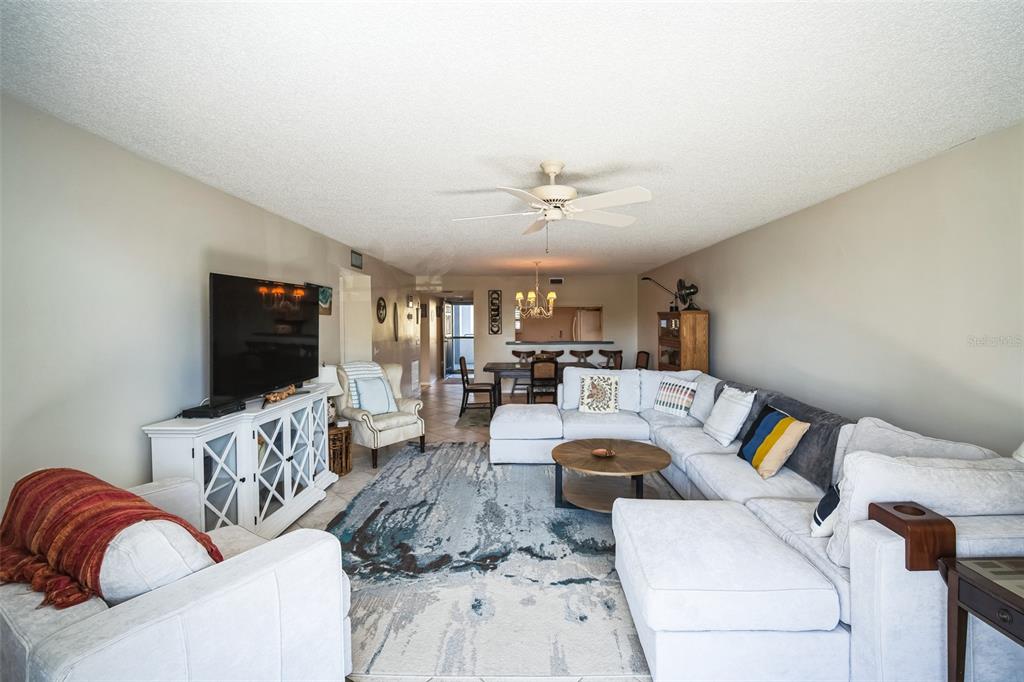 A living room features a large sectional sofa, a patterned area rug, and a television console — 1000 RIVERSIDE DRIVE UNIT B102, PALMETTO, FL