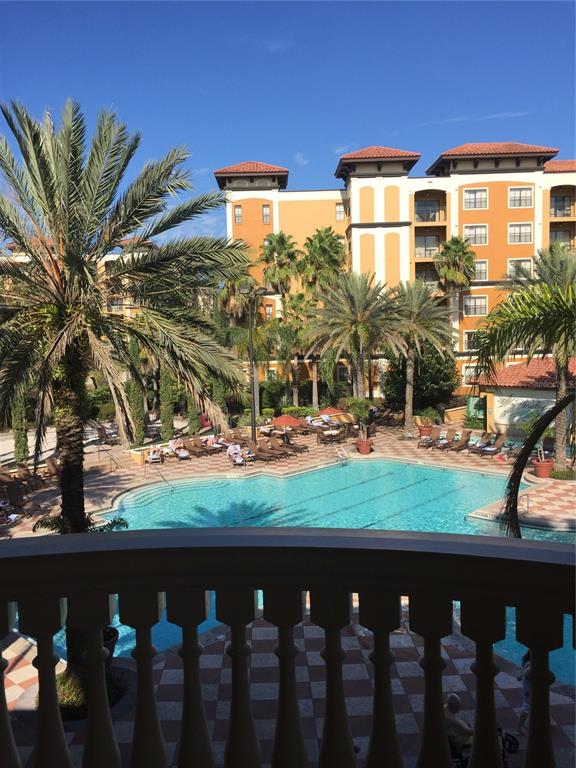 A view from a balcony overlooking a swimming pool and a multi-story Mediterranean-style building — 12544 FLORIDAYS RESORT DRIVE UNIT 612B, ORLANDO, FL