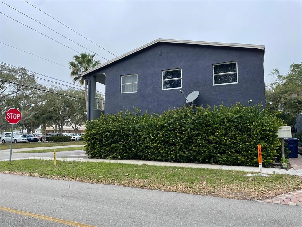 A dark blue two-story building sits behind a large hedge next to a stop sign — 2251 GRAND AVENUE, FORT MYERS, FL