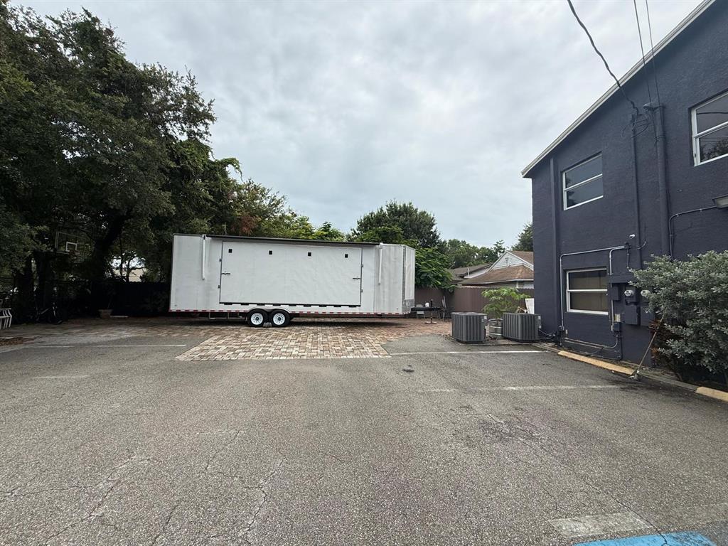 A white trailer is parked on a paved lot next to a dark gray building — 2251 GRAND AVENUE, FORT MYERS, FL