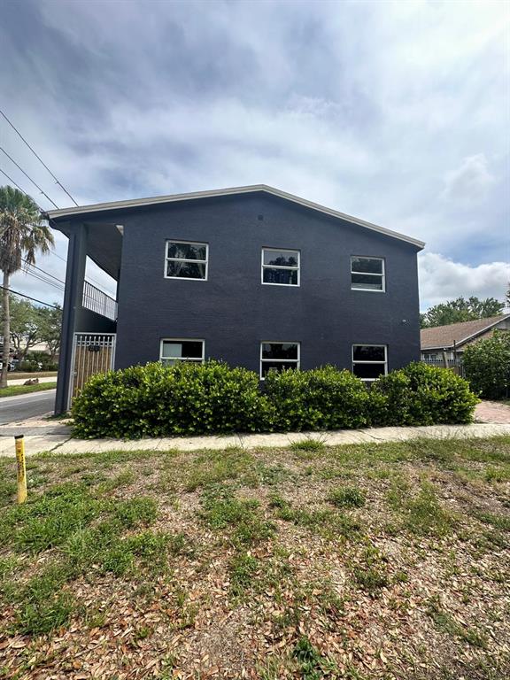 A two-story, dark-painted apartment building features a side staircase and a row of bushes — 2251 GRAND AVENUE, FORT MYERS, FL