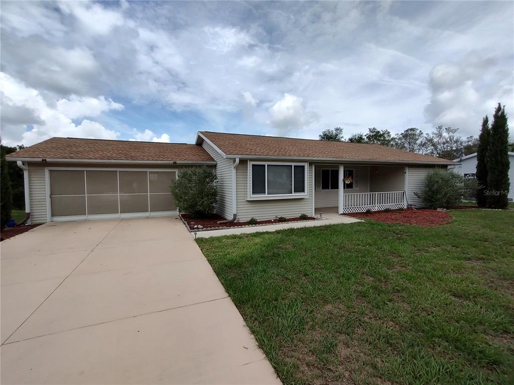 A single-story house with light siding, a tan roof, and a concrete driveway — 11440 SW 84TH AVENUE ROAD, OCALA, FL