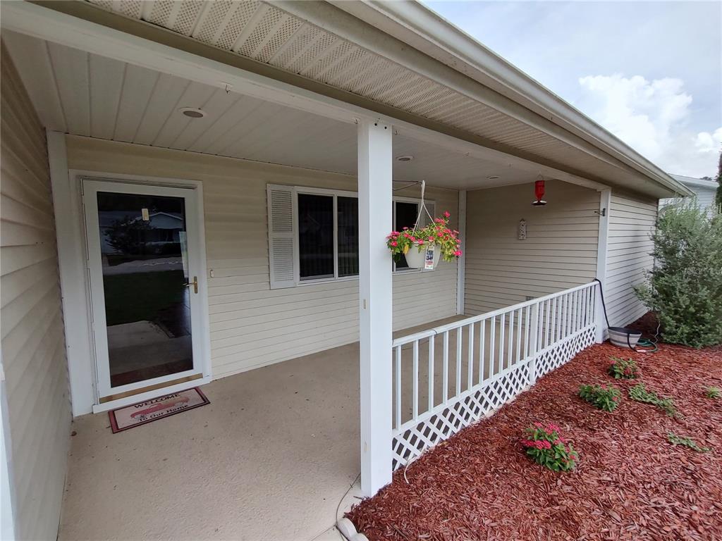 A covered front porch features light-colored vinyl siding, a white railing, and a concrete floor — 11440 SW 84TH AVENUE ROAD, OCALA, FL