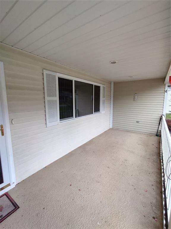 A covered porch features beige vinyl siding, a large window with shutters, and concrete flooring — 11440 SW 84TH AVENUE ROAD, OCALA, FL