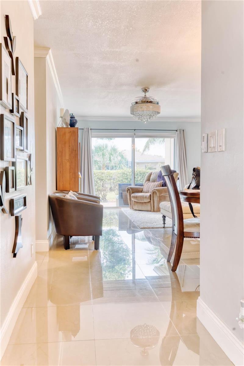 A hallway with tile floors leads to a living area with a sliding glass door — 8751 Chevy Chase Drive # 150, Boca Raton FL 33433, BOCA RATON, FL
