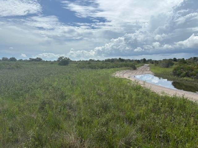 A dirt path leads through a grassy field with a small puddle under a cloudy sky — 0 NW 308th Street, Okeechobee FL 34972, OKEECHOBEE, FL