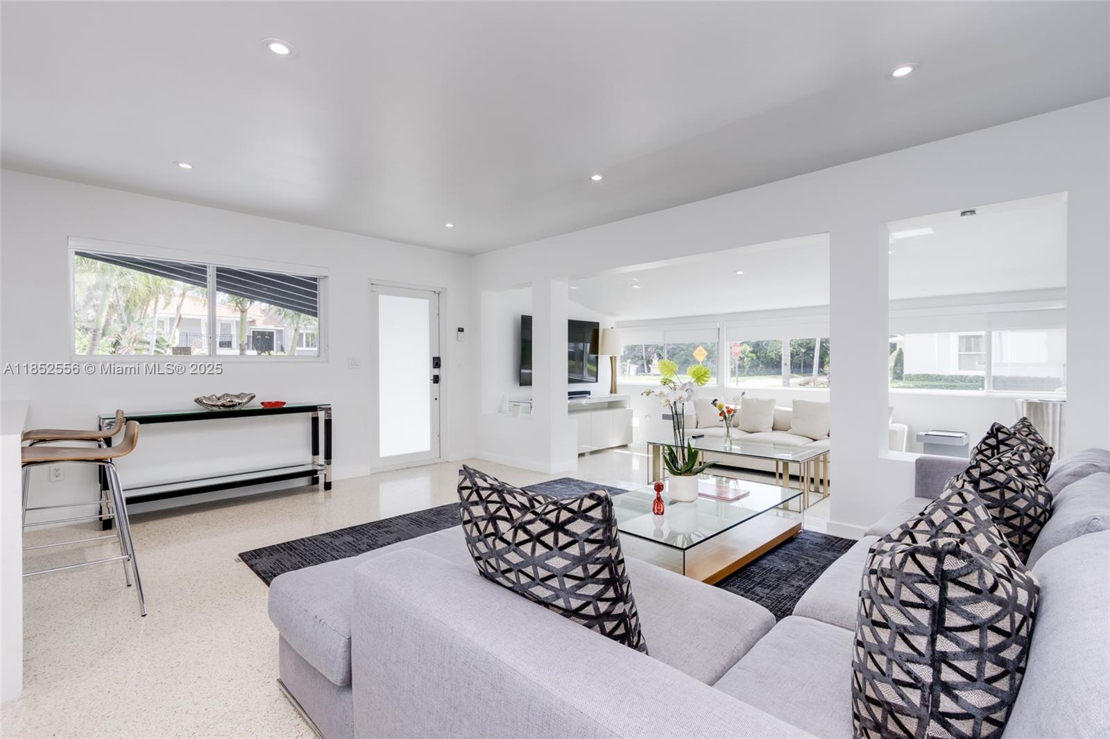A bright, modern living room features white walls, light tile floors, and two seating areas — 8290 N Bayshore Dr, Miami FL 33138, MIAMI, FL