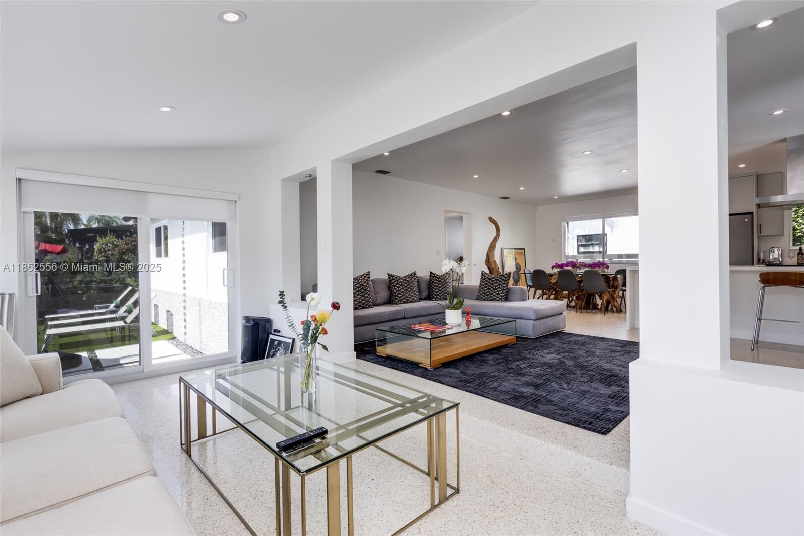 A bright, open-concept living and dining area features white walls, terrazzo flooring, and glass tables — 8290 N Bayshore Dr, Miami FL 33138, MIAMI, FL