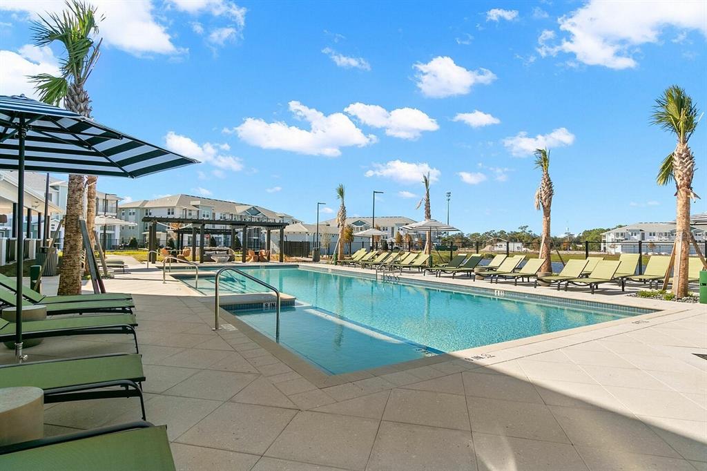 A swimming pool with lounge chairs and palm trees at an apartment complex — 5476 ANGEL WAY UNIT B1, ST CLOUD, FL