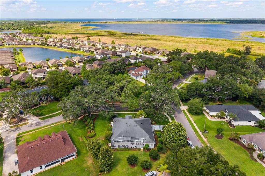 An aerial view shows a suburban neighborhood with houses, green lawns, and a large lake — 5222 HAMMOCK POINTE COURT, ST CLOUD, FL