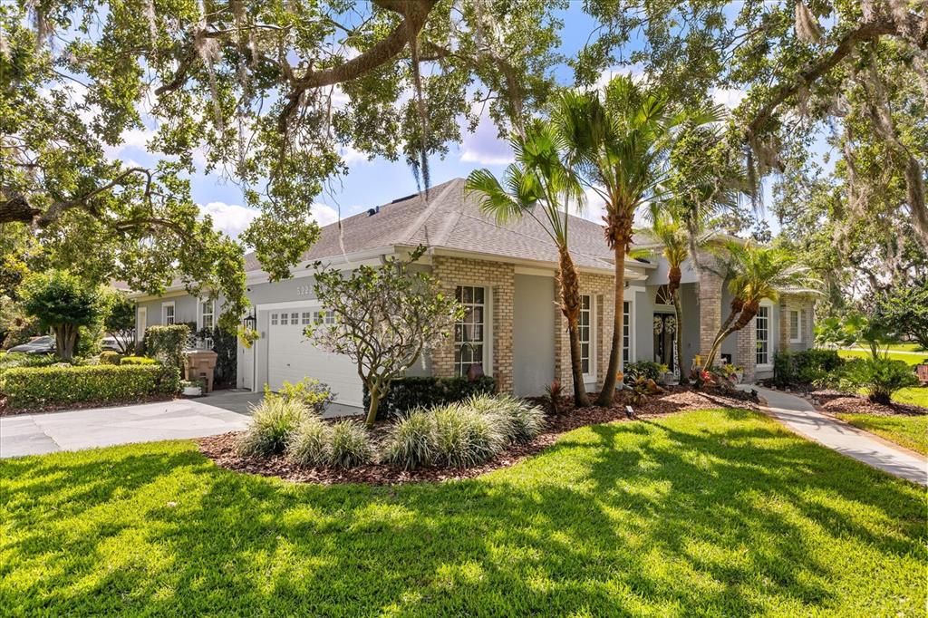 A single-story house with a brick and stucco exterior, a two-car garage, and palm trees — 5222 HAMMOCK POINTE COURT, ST CLOUD, FL