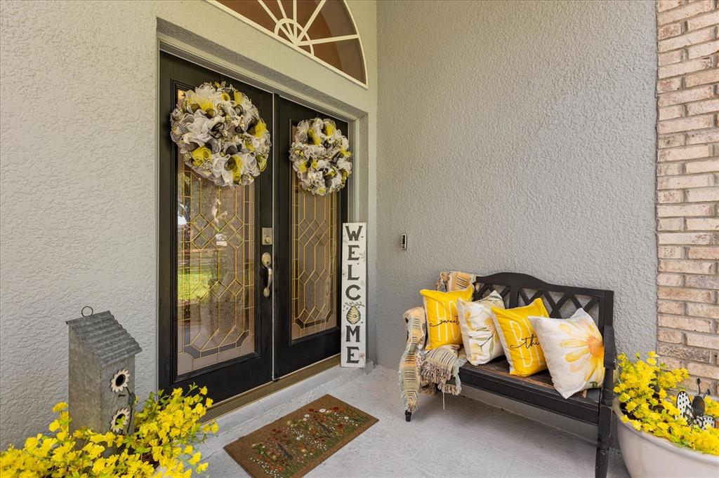 A front porch features double black doors with wreaths, a bench with yellow pillows, and decor — 5222 HAMMOCK POINTE COURT, ST CLOUD, FL