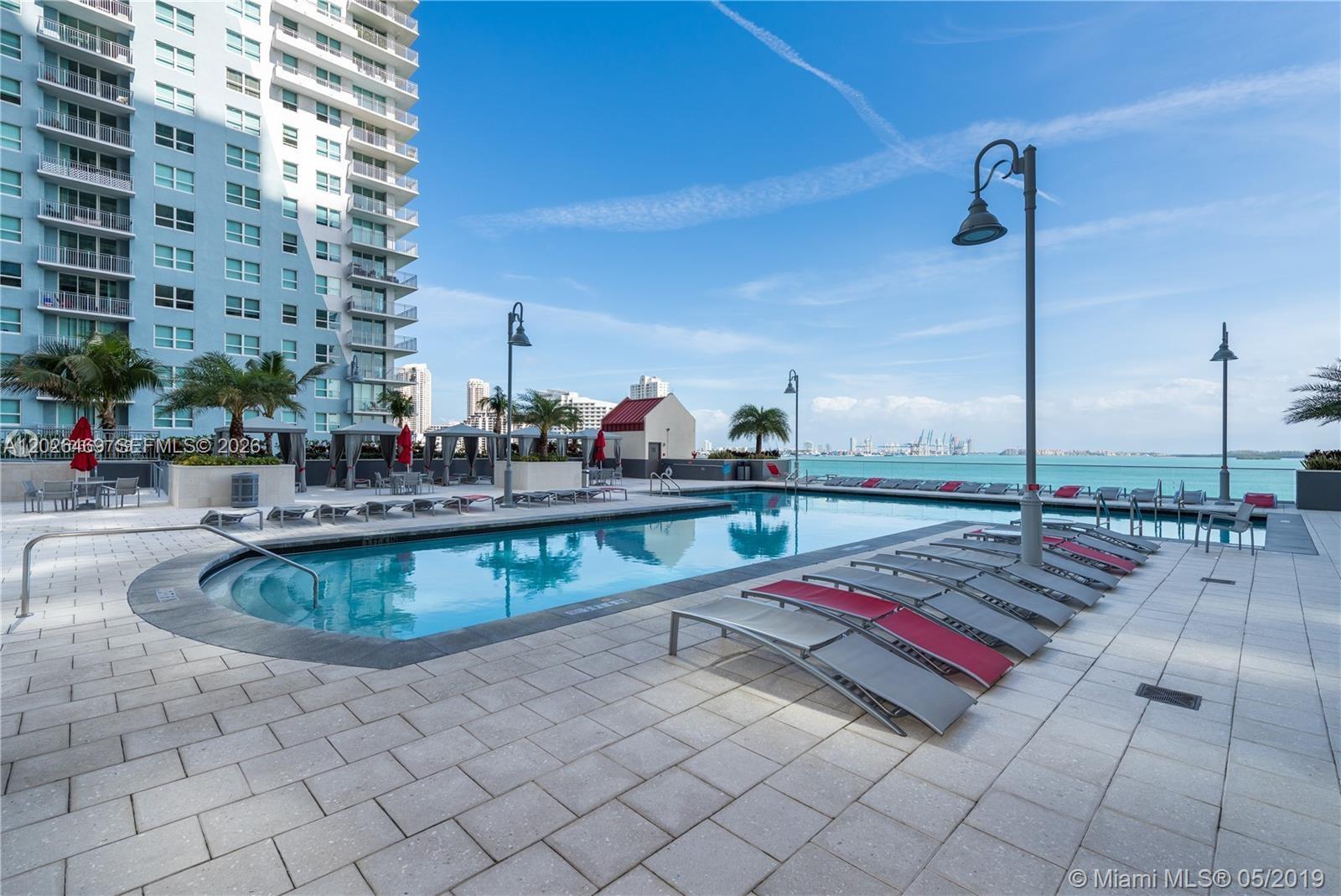 An outdoor swimming pool with lounge chairs on a paved deck overlooking the ocean — 1155 Brickell Bay Dr # 3301, Miami FL 33131, MIAMI, FL
