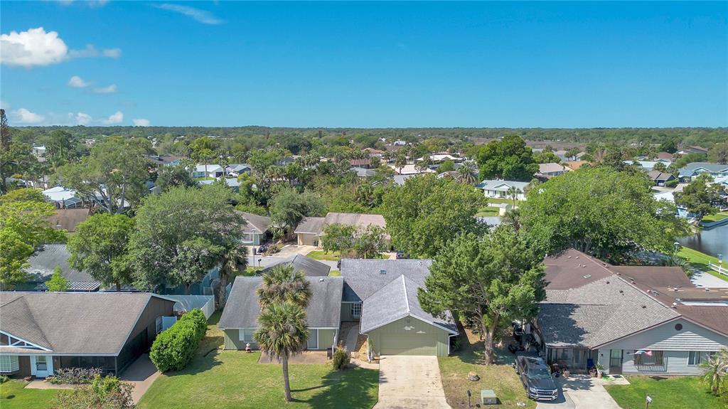 An aerial view shows a suburban neighborhood with single-family homes, green lawns, and mature trees — 16 EAGLE LANE, NEW SMYRNA BEACH, FL