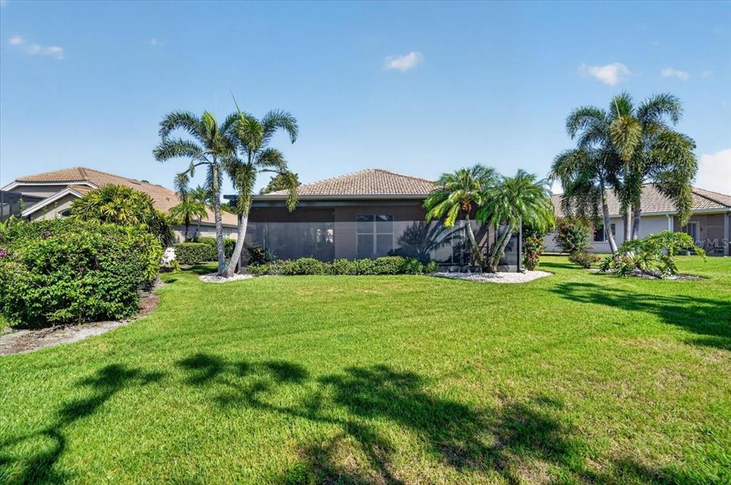 A view of a house exterior with a screened-in lanai and palm trees — 7128 DREWRYS BLUFF, BRADENTON, FL