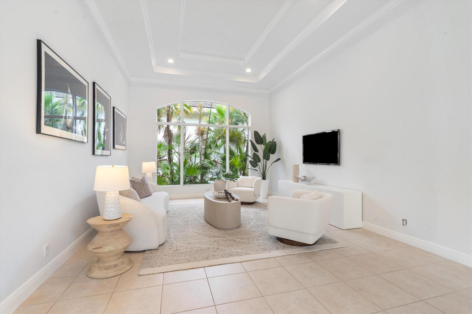 A bright living room features white furniture, a neutral area rug, and a large arched window — 15873 Double Eagle Trail, Delray Beach FL 33446, DELRAY BEACH, FL