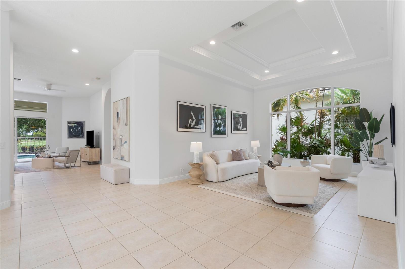 A bright, open-concept living area features white walls, tile floors, and large arched windows — 15873 Double Eagle Trail, Delray Beach FL 33446, DELRAY BEACH, FL