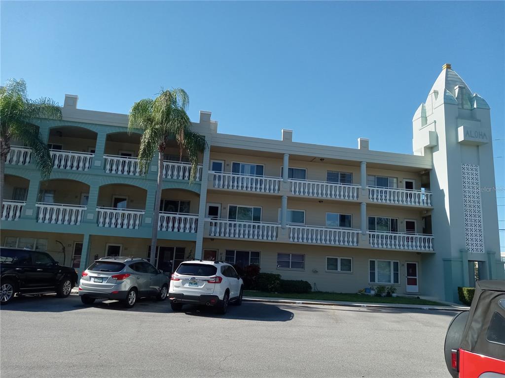 A three-story apartment building with a distinctive tower and balconies under a clear blue sky — 2331 FINLANDIA LANE UNIT 53, CLEARWATER, FL