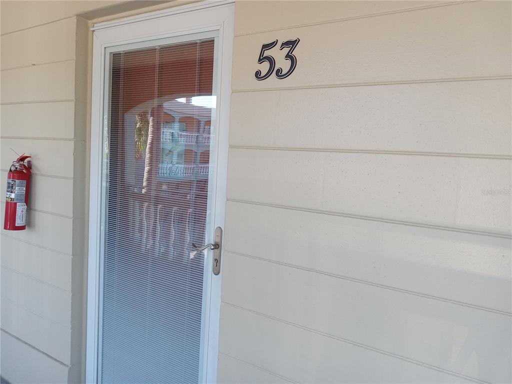 A white exterior door with a glass storm door and the number 53 above it — 2331 FINLANDIA LANE UNIT 53, CLEARWATER, FL