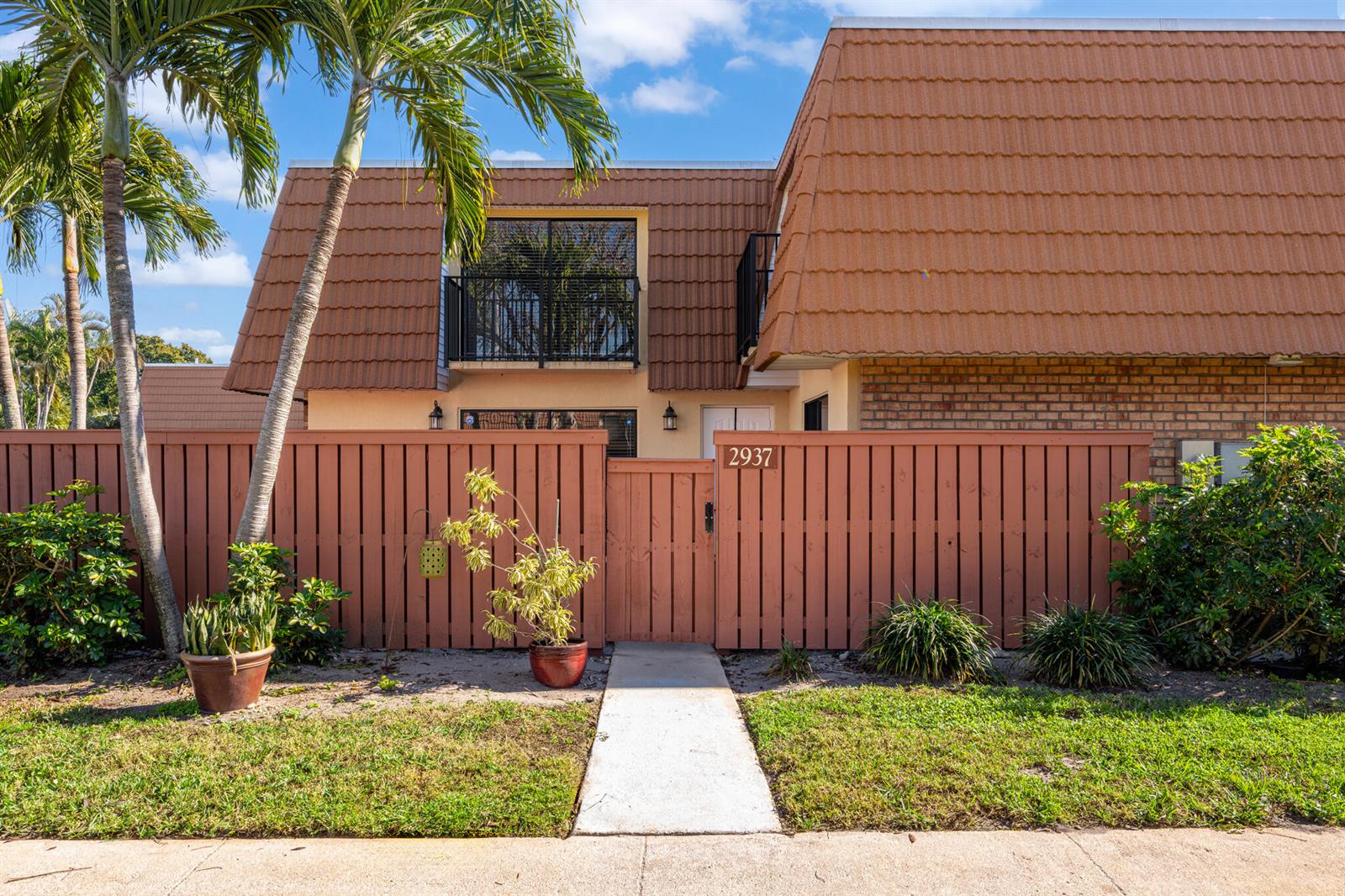 A two-story townhouse exterior features a brown tiled mansard roof, a wooden fence, and a walkway — 2937 SW 11th Place N, Deerfield Beach FL 33442, DEERFIELD BEACH, FL