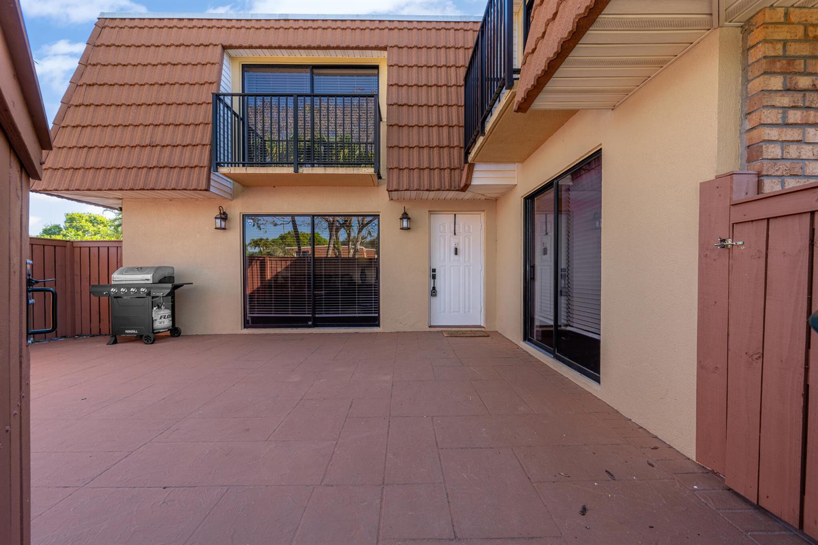 A patio with a grill, sliding glass doors, and a second-story balcony with a railing — 2937 SW 11th Place N, Deerfield Beach FL 33442, DEERFIELD BEACH, FL