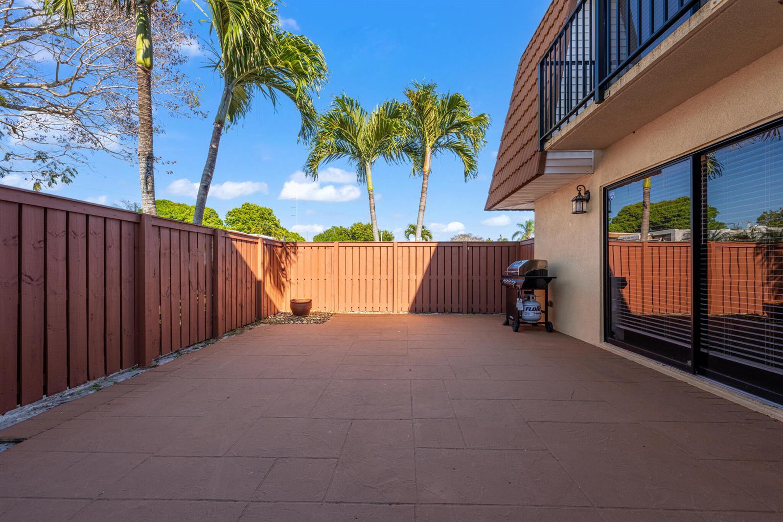 A fenced-in backyard patio features brown pavers, a grill, and several palm trees — 2937 SW 11th Place N, Deerfield Beach FL 33442, DEERFIELD BEACH, FL