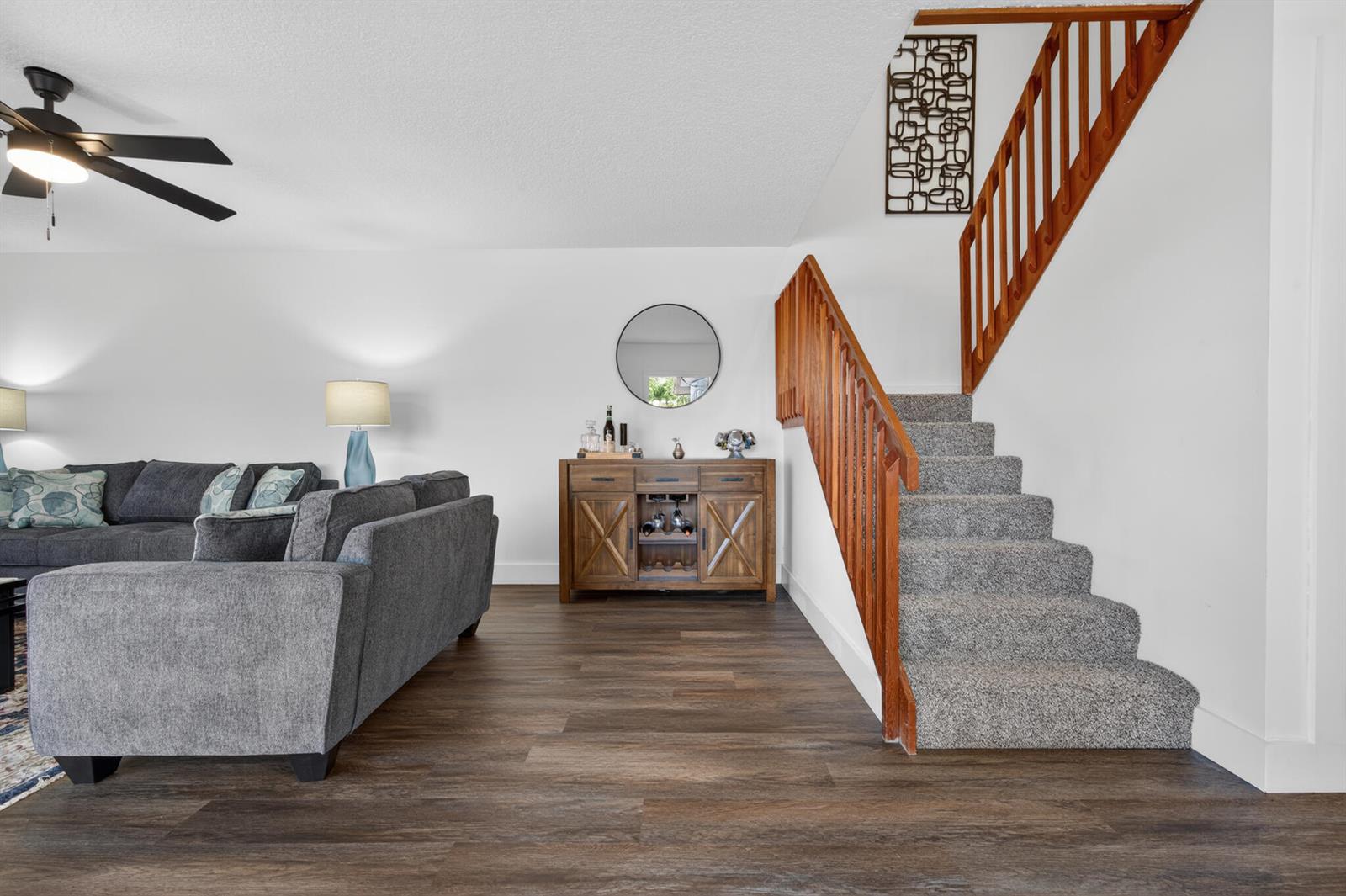 A living room features a gray sectional sofa, a wooden sideboard, and carpeted stairs — 2937 SW 11th Place N, Deerfield Beach FL 33442, DEERFIELD BEACH, FL