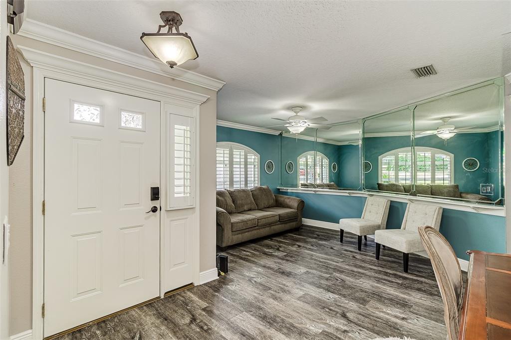 An entryway leads into a living area with teal walls, mirrored panels, and wood-look flooring — 5864 MANCHESTER DRIVE W, LAKELAND, FL